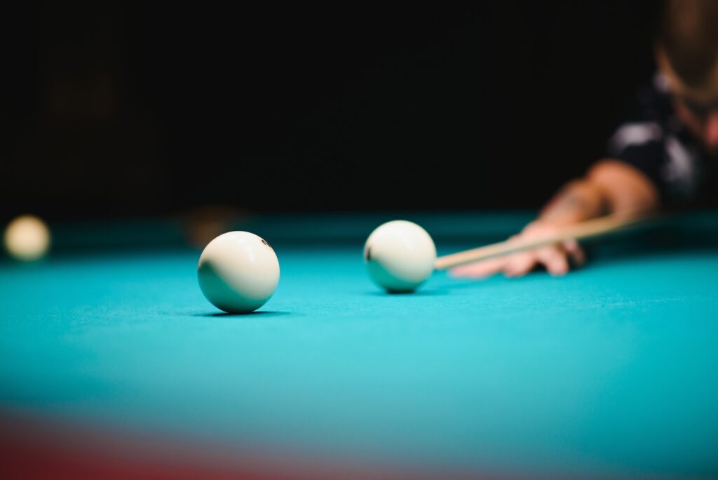 game of billiards the hand of a man with a billiard cue aims at a billiard ball